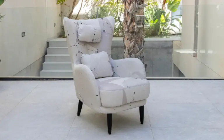 Armchair upholstered in light-toned Cosmos fabric, featuring a soft design and a subtle constellation-inspired pattern.