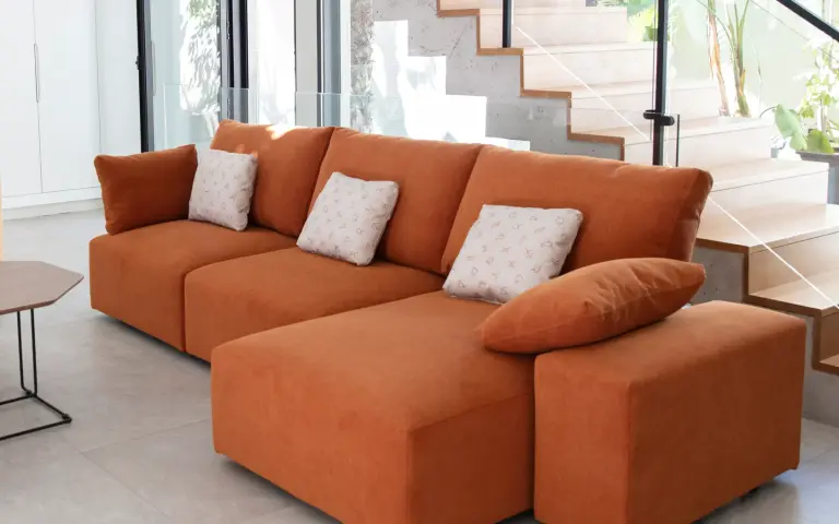 Modular sofa upholstered in Zodiaco fabric in terracotta, with matching cushions featuring zodiac symbol prints.