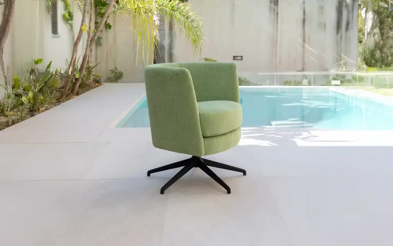 Fauteuil pivotant Peque de Fama Sofás, tapissé en vert clair, au design moderne et compact idéal comme siège d’appoint.