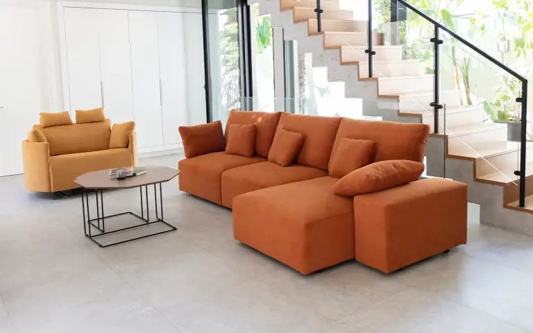 Canapé modulaire Teseo de Fama Sofás avec dossier haut et coussins moelleux, assise souple et enveloppante, accompagné d’un fauteuil relax couleur moutarde.